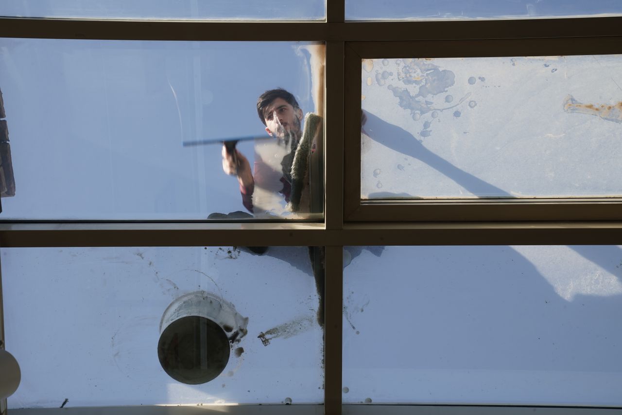 hero-img A male window cleaner washing the exterior glass roof from above with a tool during daylight.